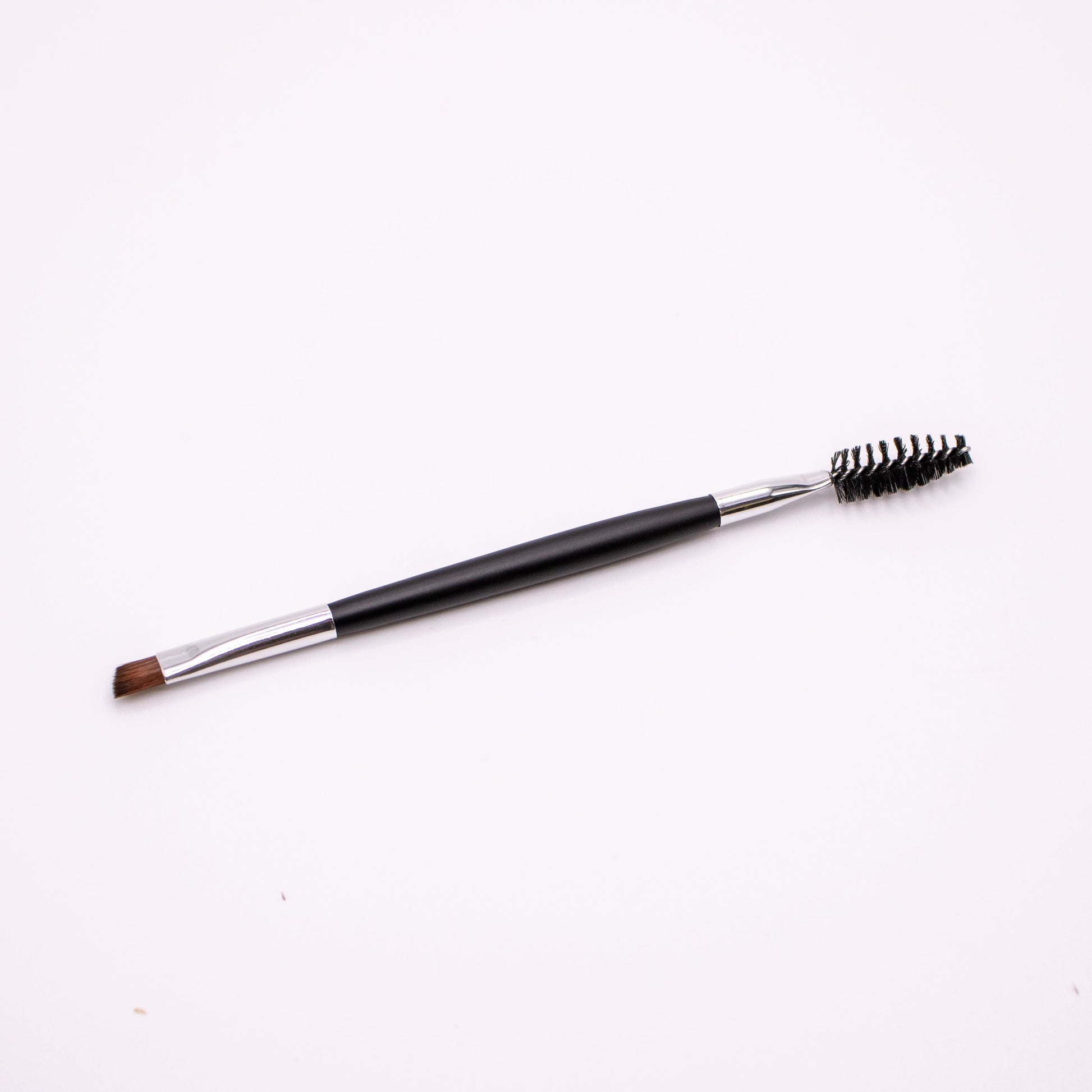 Eyebrow brush with black handle and bristles on a white background